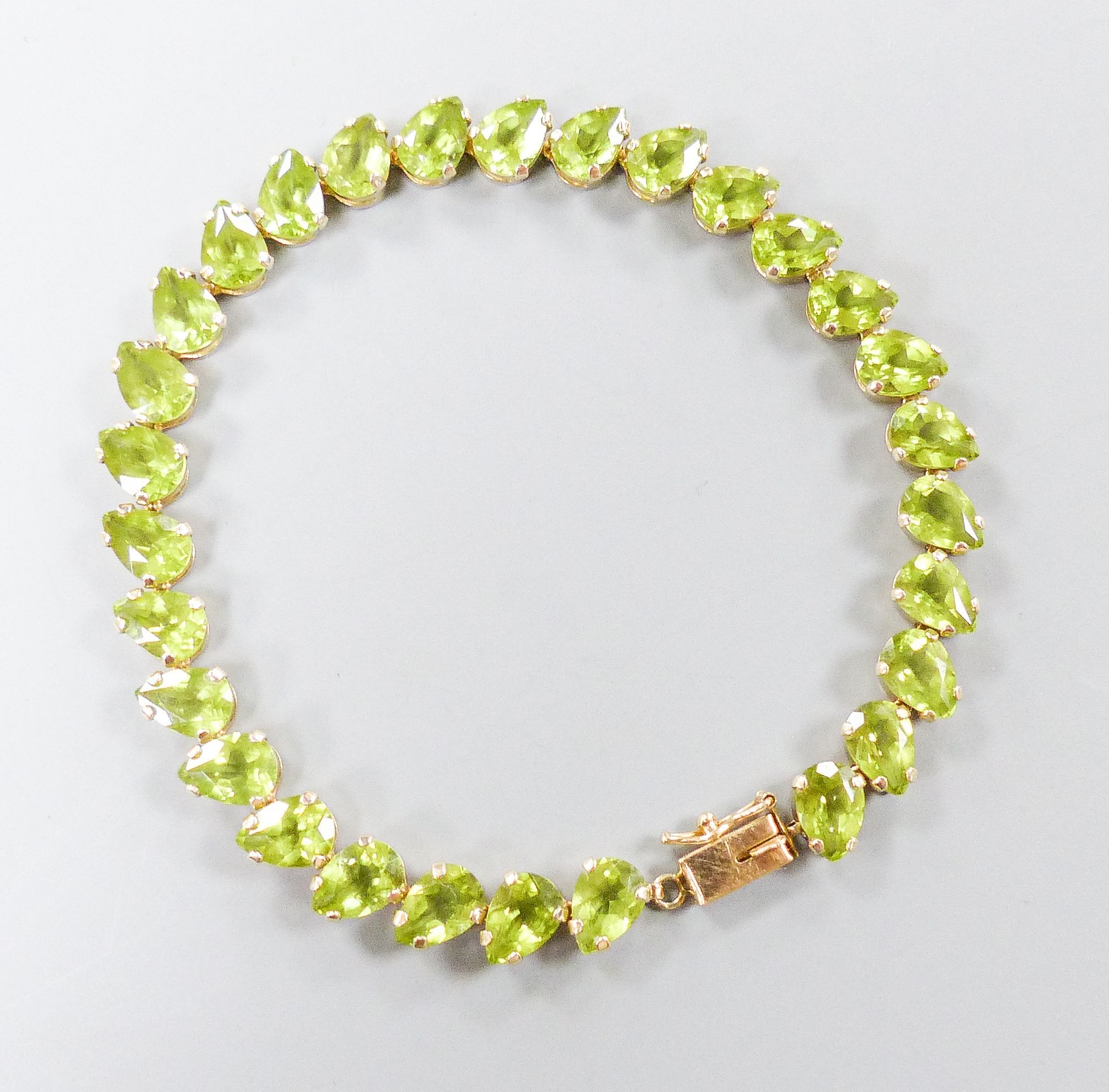 A modern 10k and pear cut peridot set line bracelet, 19cm, gross weight 9.4 grams.